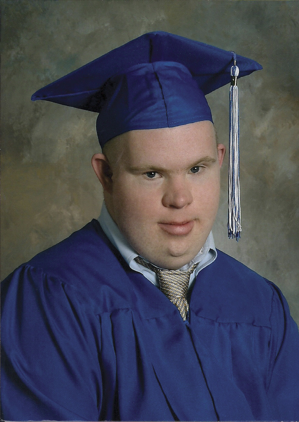 A graduation headshot of Ethan Saylor, a young man with Down syndrome who wears a blue graduation gown and cap.